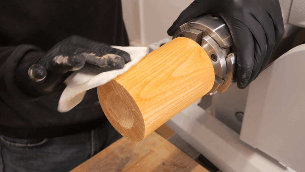 Holzrohling wird mit Hilfe eines Tuchs mit Schleifgrund eingestrichen.